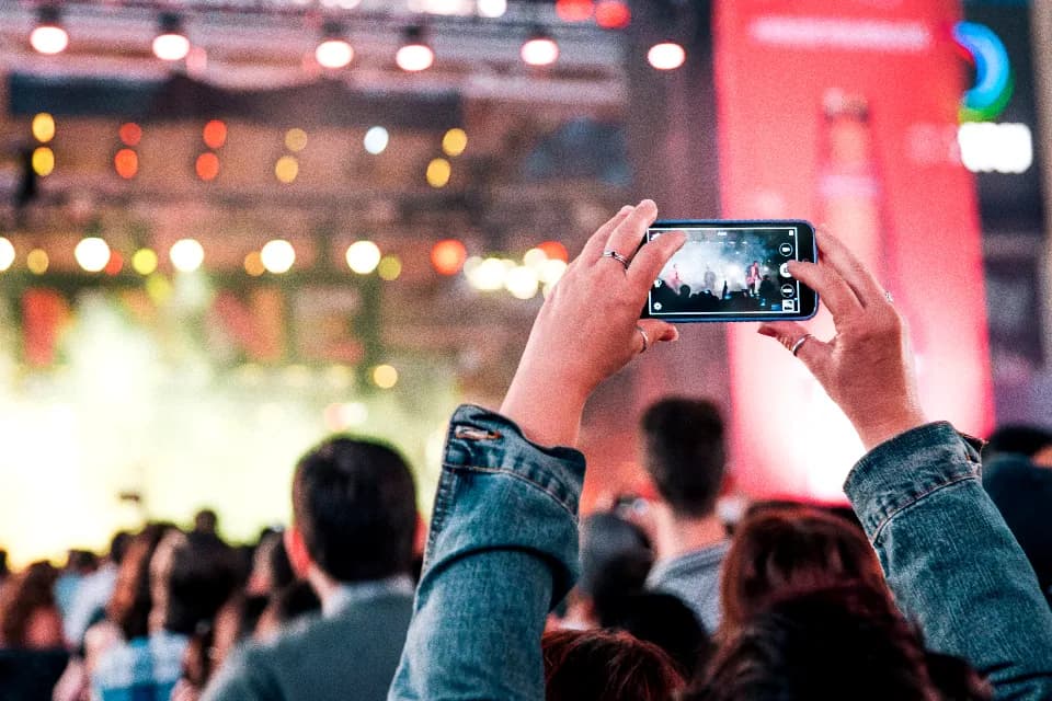 Someone holding a phone above a crowd, filming a show