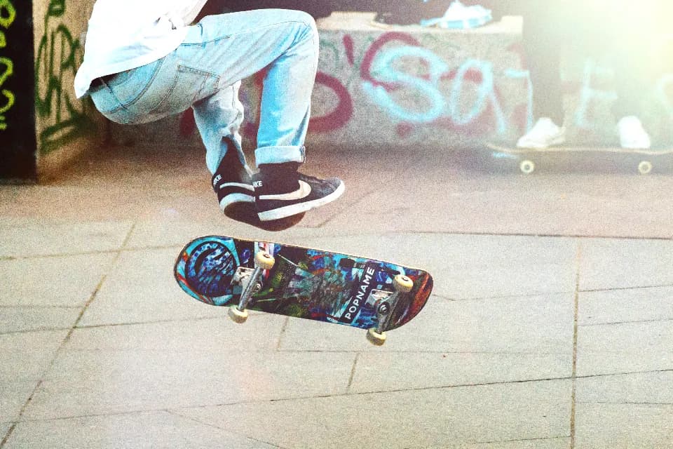 A skateboard mid-flip in front of a graffiti-covered wall