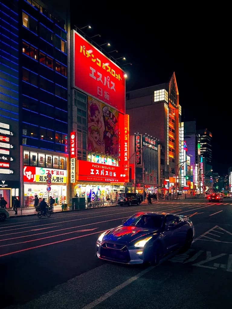 Cars waiting on a street washed in red and white signage light