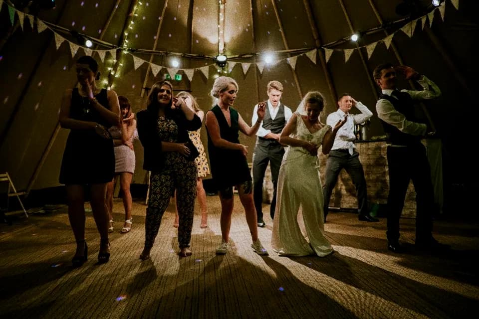 A group dancing together outdoors under strings of warm bulbs